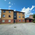 Three-storey brick apartment building under blue sky.