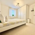 Modern white bedroom with double bed and closet.