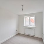 Empty white room with window and radiator.
