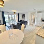 Bright open-plan kitchen and living area with sofas.