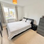 Bright bedroom with double bed and window view.