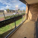 Sunny balcony view with road and building.