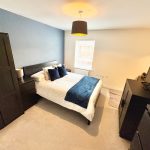 Modern bedroom with black furniture and double bed.