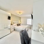 Modern bedroom with large mirror and cosy decor.