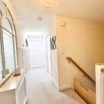 Bright hallway with large mirror and staircase.