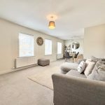Spacious modern living room with grey sofa and dining table.