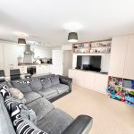 Modern living room with kitchen and large sofa.