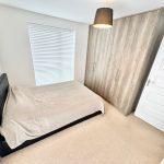 Minimalist bedroom with bed, wardrobe, and lamp.