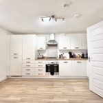 Modern white kitchen with wooden floor.