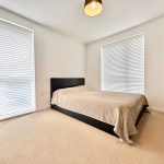 Minimalist bedroom with double bed and closed blinds.