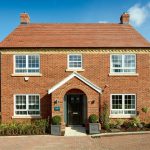 Modern red brick house with white windows and garden.