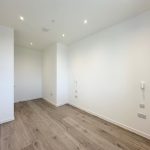Minimalist empty room with wooden floor and white walls.