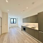Modern kitchen with wooden flooring and sleek cabinets.