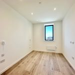 Empty room with wooden flooring, single window view.
