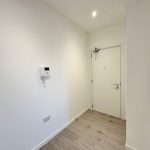 Modern minimalist hallway with white door, wood floor.
