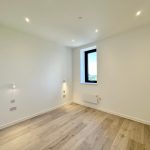 Minimalist white room with wooden floor and window.