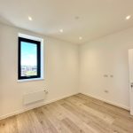Modern empty room with window and wooden floor.