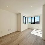 Bright empty room with wooden floor and large windows.