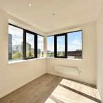 Bright empty room with large windows and city view.