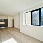Modern kitchen with large window and wooden floor.