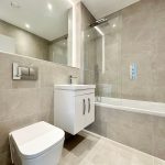Modern bathroom with shower and white fixtures.