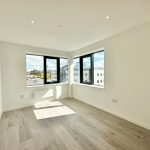 Bright unfurnished room with large windows and city view.