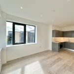Modern open-plan kitchen in apartment with large windows.