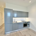 Modern kitchen with grey cabinets and wooden floor.