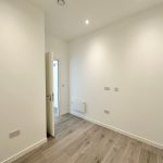 Empty white room with wooden floor and open door.