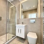 Modern bathroom with shower, sink, toilet, and towel rail.