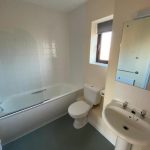 Bathroom with bath, toilet, sink and mirror.
