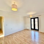 Bright empty room with wooden flooring and balcony door.