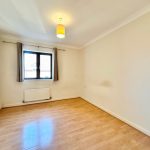 Empty bedroom with wooden floor and single window.
