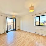 Spacious empty room with wooden floor and balcony