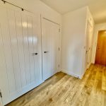 Modern hallway with wooden floor and white doors.