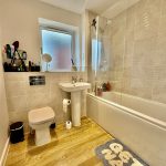 Modern bathroom with tiled walls and wooden floor.