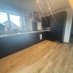 Modern kitchen with wooden floor and dark cabinets.