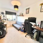 Home office with desk, sofa, and decorations.