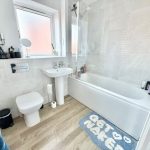 Modern bathroom with bath, toilet, basin, and window.