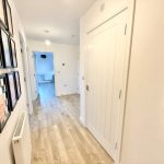 Bright hallway with wooden flooring and wall art.