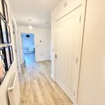 Modern hallway interior with framed art and wooden floor.