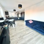 Modern open-plan kitchen living area with blue sofa.