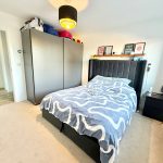 Modern bedroom with double bed and wardrobe.