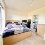 Bright bedroom with bed and computer desk setup.