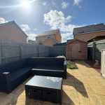 Sunny garden with patio and wooden shed.