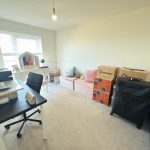 Home office with desk, chair, boxes and vanity.