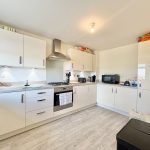 Modern kitchen with white cabinets and appliances.