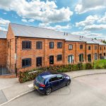 Brick terraced houses and cars on a residential street.