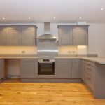 Modern kitchen with grey cabinets and wooden floor.