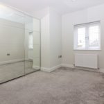 Minimalist bedroom with mirrored wardrobe and carpeted floor.